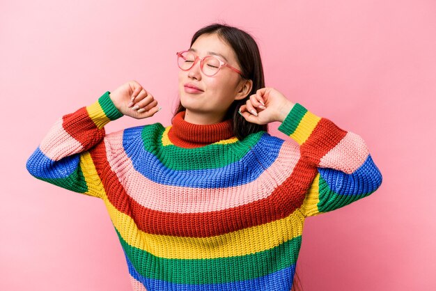 Jonge Chinese vrouw geïsoleerd op roze achtergrond strekkende armen ontspannen positie