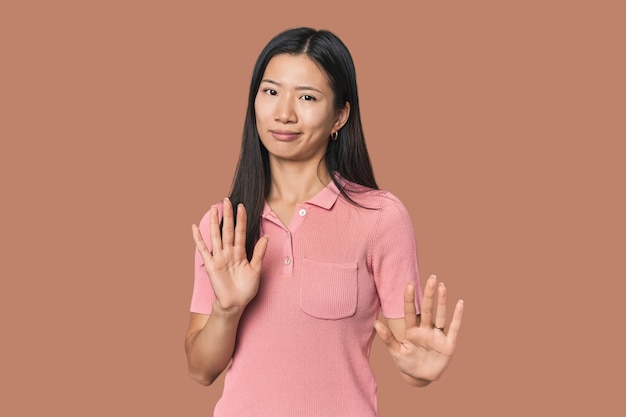 Jonge Chinese vrouw in een studio die iemand afwijst met een gebaar van walging