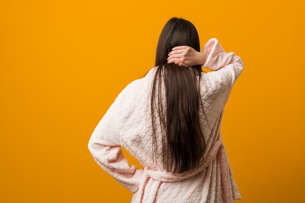 Jonge chinese vrouw in pyjama van achter het denken over iets.