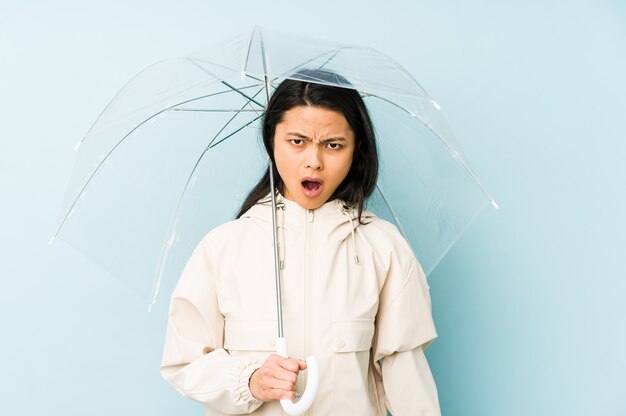 Jonge chinese vrouw met een paraplu geïsoleerd blij en zorgeloos met een vredessymbool met vingers.