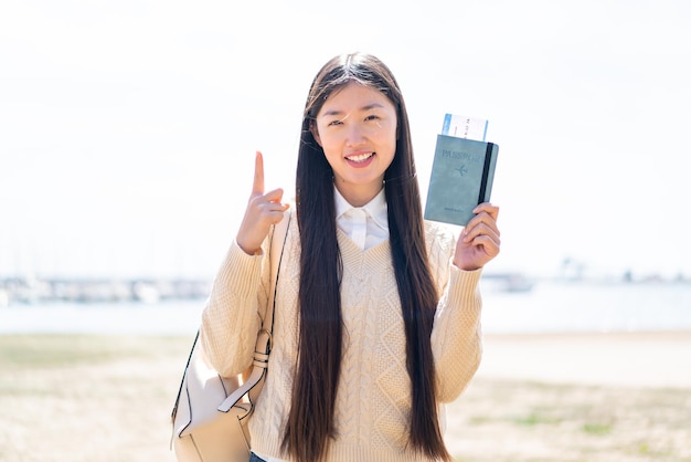 Jonge Chinese vrouw met een paspoort buitenshuis die een geweldig idee benadrukt