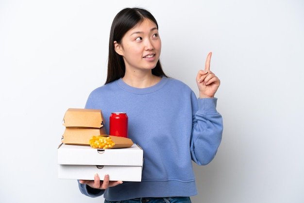 Jonge Chinese vrouw met fastfood geïsoleerd op een witte achtergrond die een geweldig idee benadrukt