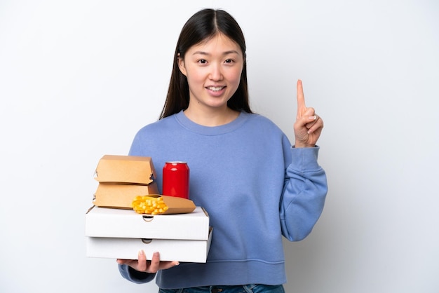 Jonge Chinese vrouw met fastfood geïsoleerd op een witte achtergrond die een geweldig idee benadrukt