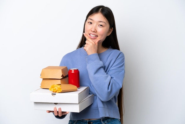 Jonge Chinese vrouw met fastfood geïsoleerd op een witte achtergrond gelukkig en glimlachend