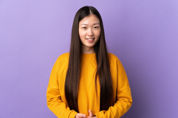 Jonge Chinese vrouw over geïsoleerde paarse muur lachen