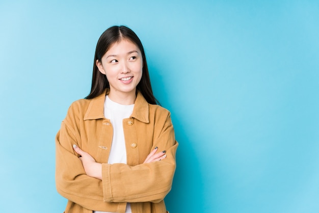 Jonge chinese vrouw poseren in een blauwe achtergrond geïsoleerd glimlachend zelfverzekerd met gekruiste armen.