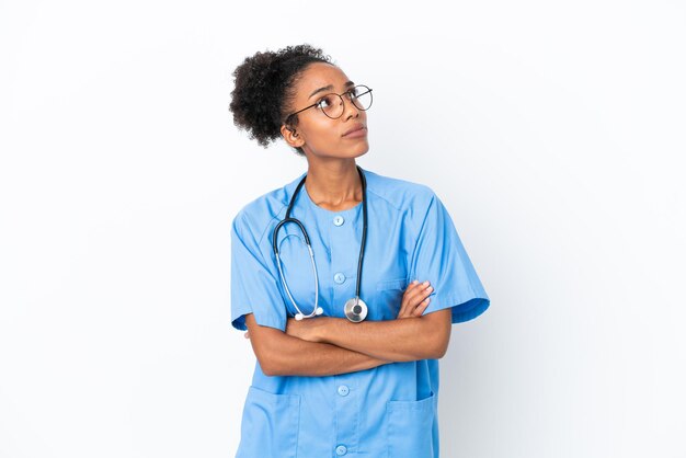 Jonge chirurg Afro-Amerikaanse arts vrouw geïsoleerd op een witte achtergrond twijfels gebaar maken terwijl het opheffen van de schouders