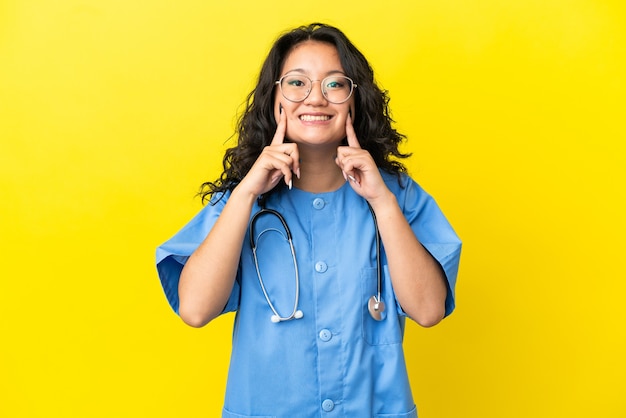 Jonge chirurg arts aziatische vrouw geïsoleerd op gele achtergrond glimlachend met een gelukkige en aangename uitdrukking