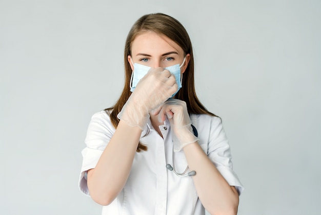 jonge chirurg arts in beschermende handschoenen latex dragen van medische masker op het gezicht. Coronavirus (COVID-19