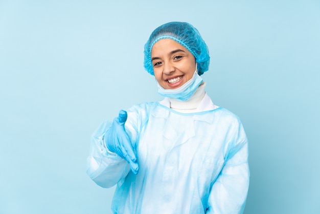 Jonge chirurg Indiase vrouw in blauwe uniform handen schudden voor het sluiten van een goede deal