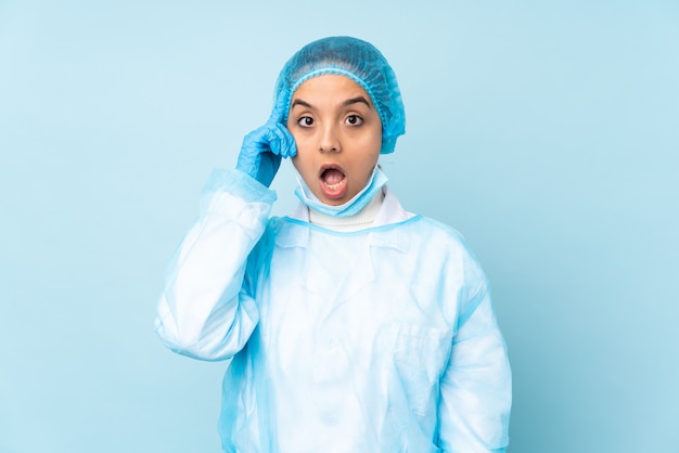 Jonge chirurg vrouw in blauw uniform heeft zojuist iets gerealiseerd en heeft de oplossing bedacht
