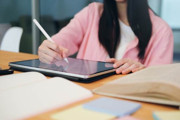 Jonge collage student met behulp van computer en mobiel apparaat online studeren. Onderwijs en online leren.