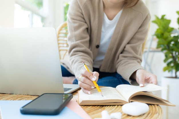 Jonge collagestudent met behulp van computer en mobiel apparaat die online studeertxA