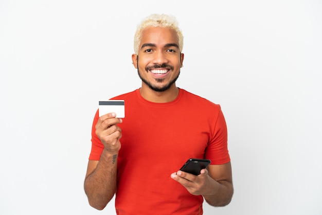 Jonge Colombiaanse knappe man geïsoleerd op een witte achtergrond kopen met de mobiel met een creditcard