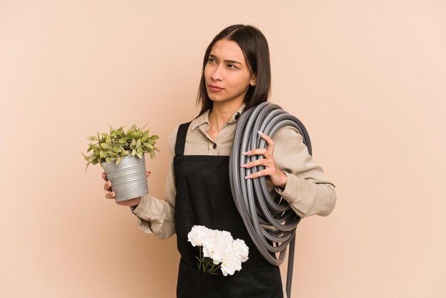 Jonge Colombiaanse tuinman houdt een plant en tuinslang vast om de natuur te koesteren.