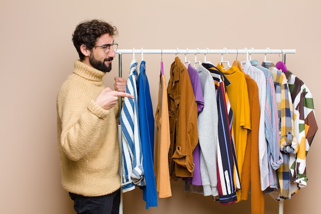 Jonge cool berded man met kleren tegen vlakke muur