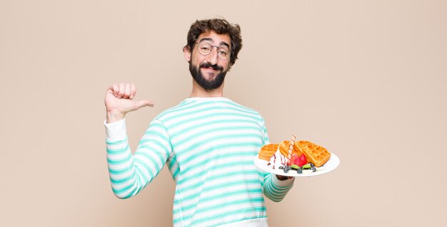 Jonge cool man met wafels tegen vlakke muur.