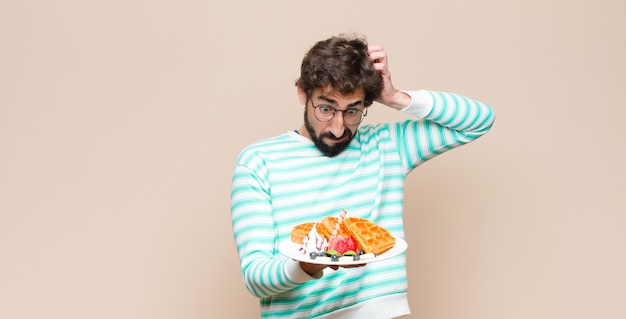 Foto jonge cool man met wafels tegen vlakke muur.