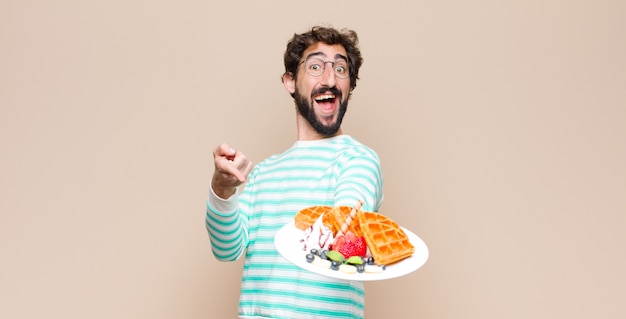 Jonge cool man met wafels tegen vlakke muur.