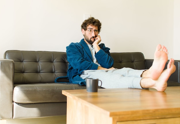 Jonge cool man zittend op een bank in de woonkamer tv kijken