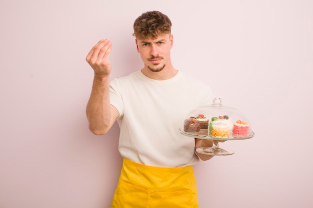 Foto jonge coole man die capice of geldgebaar maakt en je vertelt dat je het concept van zelfgemaakte taarten moet betalen