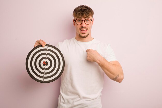 Jonge coole man die zich gelukkig voelt en naar zichzelf wijst met een opgewonden dartdoelconcept