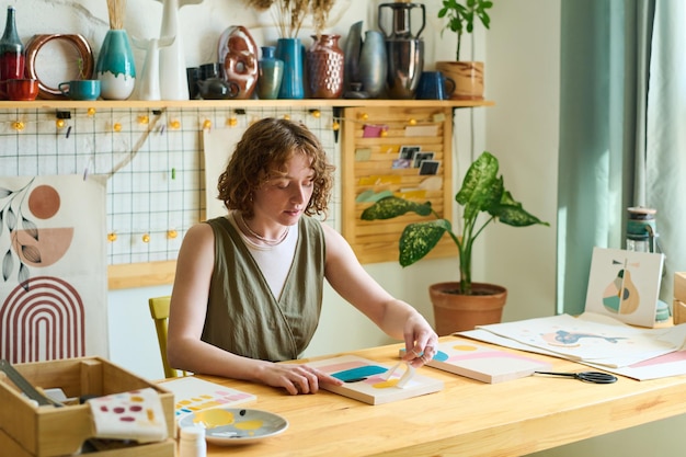 Jonge creatieve vrouw met papieren stencil die abstracte schilderkunst in studio maakt