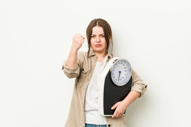 Jonge curvy vrouw die een schaal houdt die vuist toont