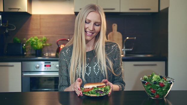 Jonge dame die hamburger verkiest boven salade