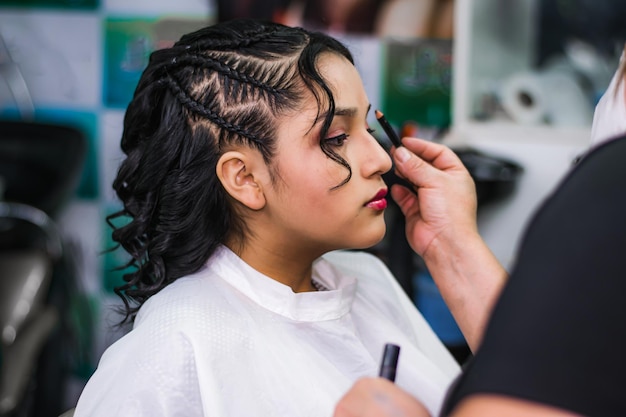 Jonge dame die make-up en haar laat doen in een professionele spa of kapsalon.