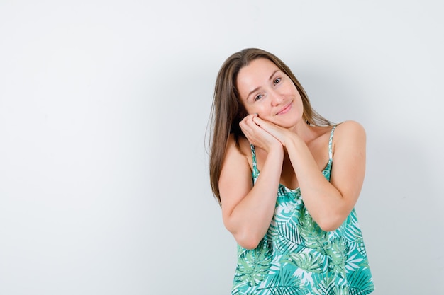 Jonge dame in blouse die haar gezicht op haar handen dempt en er slaperig uitziet, vooraanzicht.