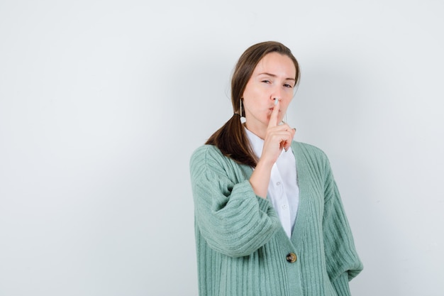 Jonge dame in blouse, vest met stiltegebaar en verstandig, vooraanzicht.