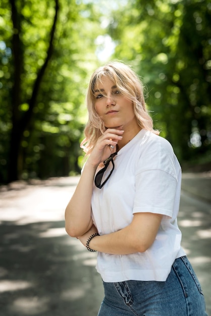 Jonge dame in jeans en een wit T-shirt heeft een geweldige tijd in de natuur in het bos. zomer