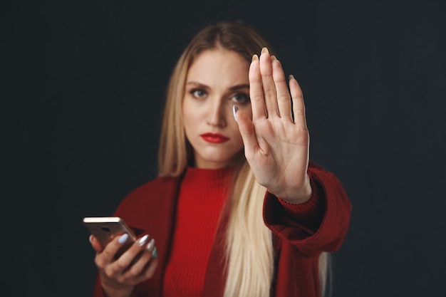 Jonge dame met stopbord met telefoon in de hand