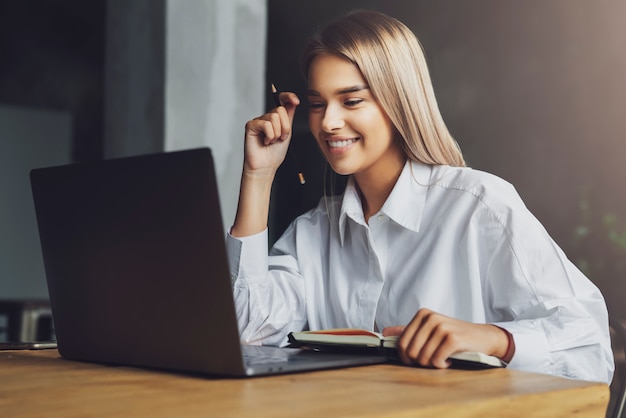 Jonge dame zit laptop kijken op het scherm en glimlachen