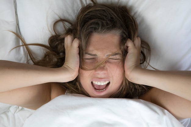 Foto jonge depressieve ongelukkige vrouw liggend in bed met gezondheidsproblemen schreeuwenkaterdepressieslaaploos