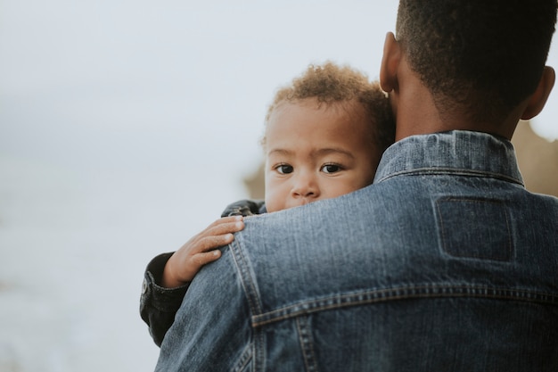 Jonge die jongen door zijn papa in openlucht wordt vervoerd