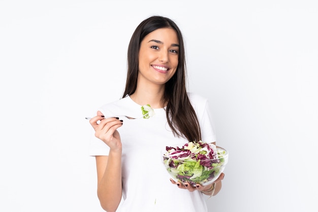 Jonge die vrouw met salade op witte muur wordt geïsoleerd