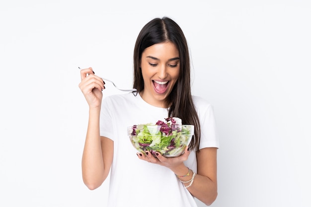 Jonge die vrouw met salade op witte muur wordt geïsoleerd