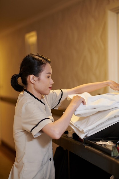 Jonge dienstmeisje in uniform die handdoeken verandert in hotelkamers.