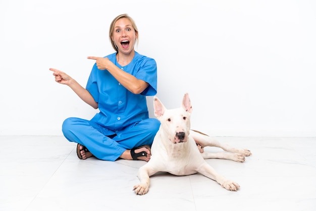 Jonge dierenarts Engelse vrouw zittend op de vloer met hond verrast en wijzende kant