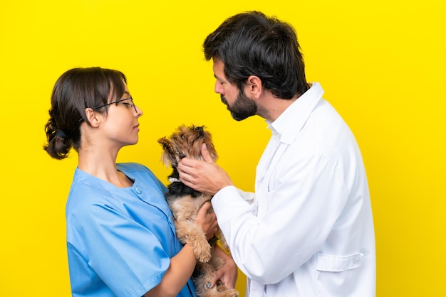 Jonge dierenarts paar met hond geïsoleerd op gele achtergrond