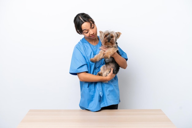 Jonge dierenarts vrouw met hond op een tafel geïsoleerd op een witte achtergrond met droevige uitdrukking