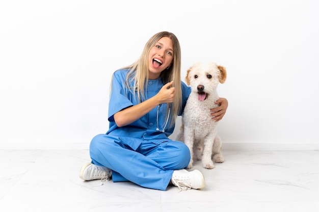 Jonge dierenarts vrouw met hond zittend op de vloer een overwinning vieren