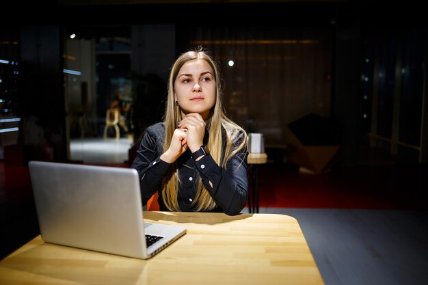 Jonge doelgerichte vrouw die werkt aan een nieuw zakelijk project op kantoor. Gekleed in een zwart overhemd.