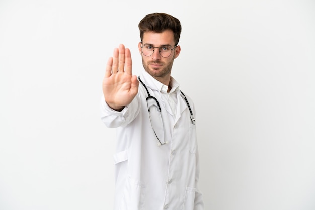 Jonge dokter blanke man over geïsoleerd op een witte achtergrond, gekleed in een doktersjurk en stopbord maken