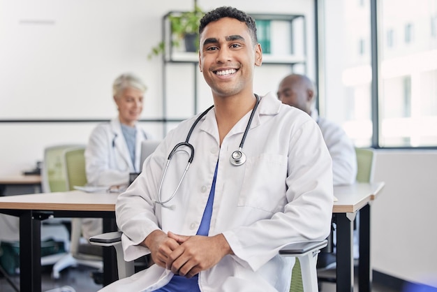 Jonge dokter man en portret aan ziekenhuisbalie met glimlach voor gezondheidszorgplanning en teamwerk Professionele leider artsen en expert in gezondheid, wellness en gelukkig in kliniek met groep aan tafel