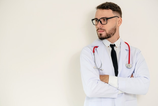 Jonge dokter met armen kruis op witte achtergrond.