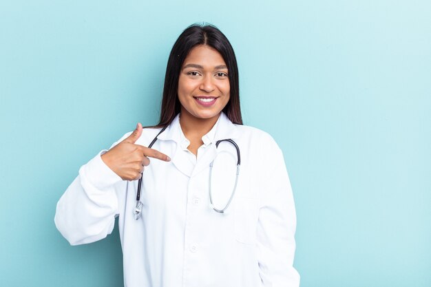 Jonge dokter Venezolaanse vrouw geïsoleerd op blauwe achtergrond persoon die met de hand wijst naar een shirt kopieerruimte, trots en zelfverzekerd