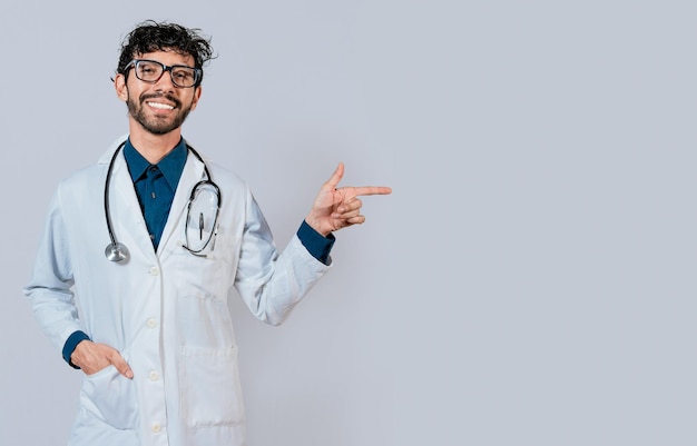 Jonge dokter wijst een promotie met zijn vinger Knappe dokter wijzend op advertentieruimte geïsoleerd Gelukkige dokter die met de vinger naar rechts wijst